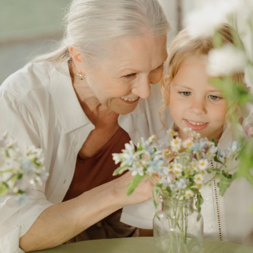 elderly woman watering flowers with her granddaughter